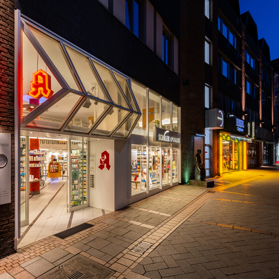 Schiller Apotheke Iserlohn bei Nacht. Die Fassade ist schön beleuchtet.